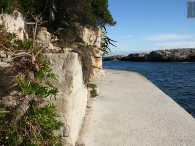 Per scovare la scritta ci basta scarpinare alla sinistra della spiaggia camminando su un basso muretto che costeggia la cala